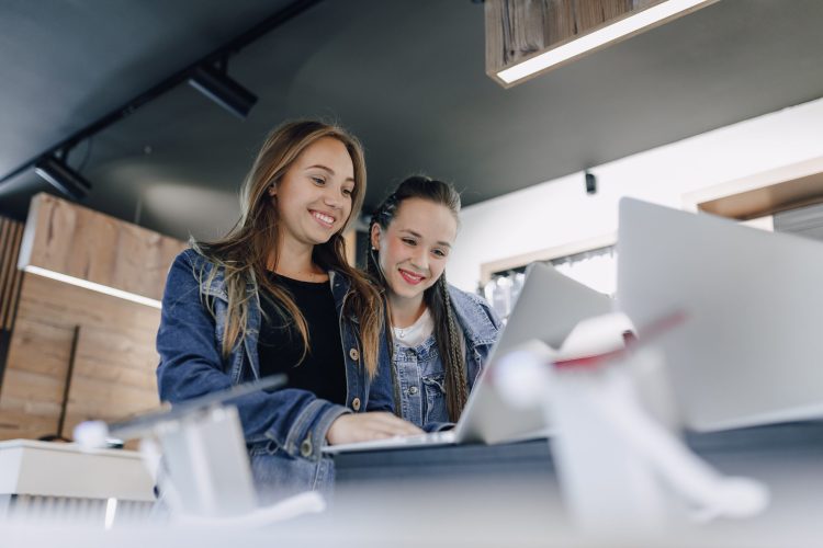 young attractive girls in an electronics store use a laptop at an exhibition. concept of buying gadgets and going to an electronics store.